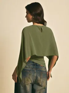 Detalle de la elegante blusa de gasa verde oliva con mangas capa y pantalones vaqueros.