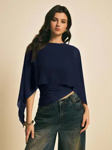 Detalle de la elegante blusa de gasa azul marino con mangas capa, textura refinada.