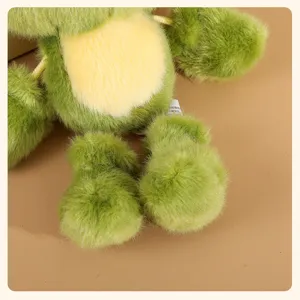 Close-up detail of cute green plush frog doll pendant, soft toy keychain with fluffy texture.