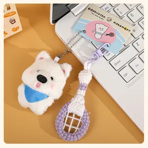 Detailed view of cute white puppy plush keychain with crochet badminton racket pendant.