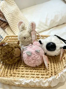 Llaveros de peluche tiernos en cesta, detalles suaves y peludos de pequeños animales.