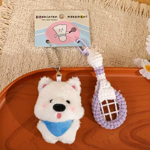 Close-up detail of cute white dog plush keychain with handmade crochet badminton racket.