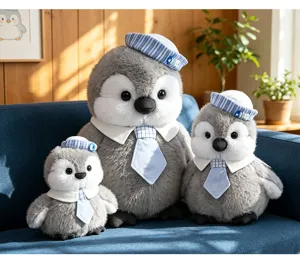Details van schattige grijze pinguïn pluche knuffels met matrozenhoeden en stropdassen op bank.