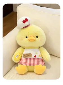 Gros plan de la jolie poupée en peluche de canard jaune avec toque de chef et tablier doux.