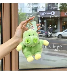 Green plush dinosaur keychain detail showing cute button eyes and soft stuffed body pendant.