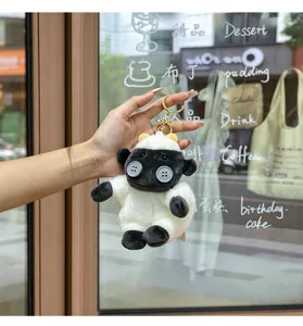 Detailed close-up of cute plush sheep keychain featuring button eyes and fluffy white body.