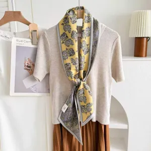 Close-up detail of luxury silk wool blend paisley neckerchief scarf in yellow and grey.