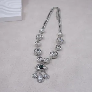 Detailed view of vintage silver crystal necklace with evil eye pendant and pearls.