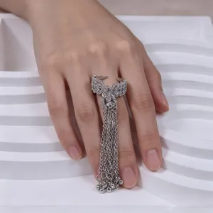 Silver bow tassel ring detail showing sparkling zircon stones and long hanging metal chains.
