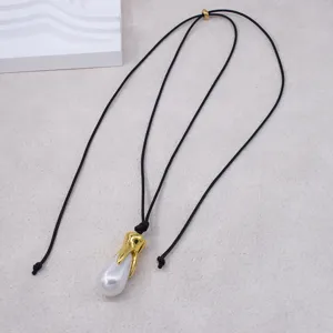 Vue détaillée du collier de perles baroque avec fermoir en métal doré et cordon noir.