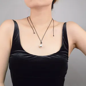 Vue détaillée d'un collier pendentif perle cordon cuir noir minimaliste, bijou élégant.
