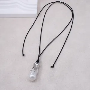Gros plan détaillé de l'élégant collier de perles en forme de goutte avec cordon noir.