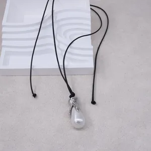 Gros plan du collier avec pendentif perle en forme de goutte et fermoir en métal argenté.