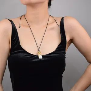 Élégant collier pendentif perle baroque avec fermoir en métal doré et chaîne en cordon noir.