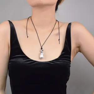 Gros plan détaillé du collier pendentif perle baroque avec griffe argentée et cordon noir.