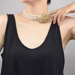 Detailed shot of multi-layer faux pearl choker necklace with striking gold starburst pendant.