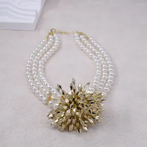 Close-up detail shot of a stunning three-layer faux pearl necklace with a statement gold firework pendant.