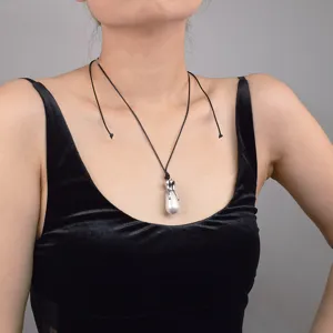 Collier de perles baroques avec pendentif griffe en métal argenté et cordon noir élégant.