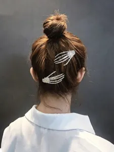 Detailed close-up view of sparkling rhinestone skeleton hand hair clips worn on hair.