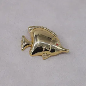 Gold tropical fish brooch detail, metal animal lapel pin, elegant fashion accessory.