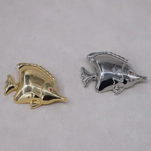 Close-up of gold and silver tropical fish brooches with shiny finish and red eyes.
