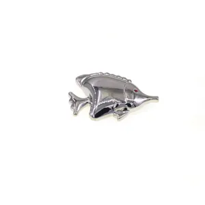 Silver metallic tropical fish brooch detail shot, glossy finish, elegant coat accessory.