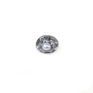 Close-up detail of vintage shell pearl brooch with irregular metallic texture for coats.