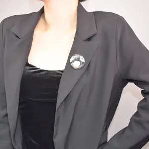 French vintage shell pearl brooch worn on black blazer lapel, elegant metallic texture accessory.