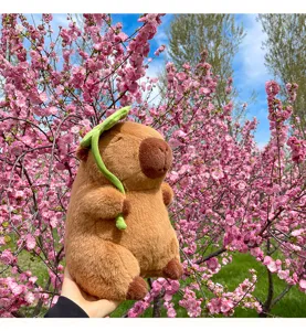 Cute capybara plush toy with green leaf accessory, soft stuffed animal doll for cute room decor.