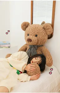 Gros plan confortable des détails de la peluche douce en forme d'ours brun avec son nœud.