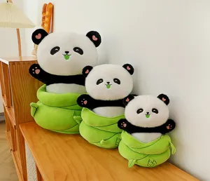 Detailed view of cute panda plush toys placed inside green bamboo shoot containers on wooden desk.