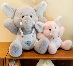 Detail view of cute grey and pink elephant plush toys sitting together on wooden shelf.