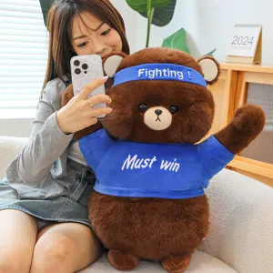 Cute brown bear plush toy with cheering headband and blue t-shirt, soft doll gift.