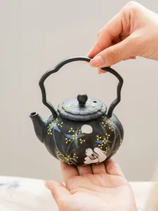 Handcrafted black ceramic teapot with painted rabbit and floral pattern for tea lovers.