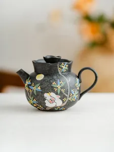 Detailed view of the black ceramic teapot featuring hand-painted rabbit and floral patterns.
