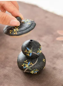 Detalle de portainciensos de cerámica con forma de calabaza, acabado mate negro y diseño floral.