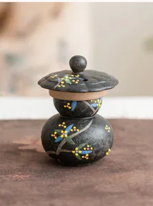 Detalle de quemador de incienso de ceramica, patron floral negro retro, decoracion mesa.