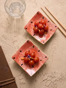 Primo piano di piatti in ceramica anguria creativi con pomodorini su sfondo beige testurizzato.