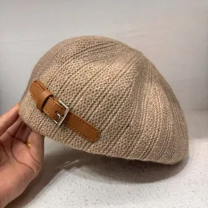 Detail view of the cozy knitted beret with leather strap, warm autumn winter hat style.