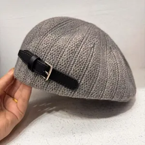 Detailed view of grey knit beret with black leather strap buckle for women chic style