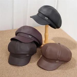 Close-up detail shot of retro PU leather newsboy caps in multiple colors with metal buckle accent.