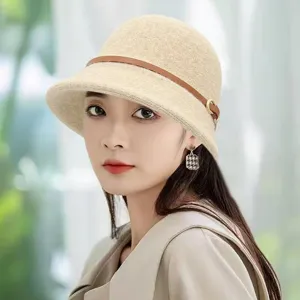 Close-up detail of the elegant beige knit bucket hat with brown leather strap decoration.