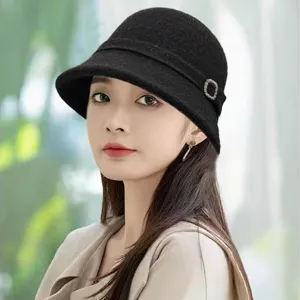 Close-up detail of the black knit cloche hat with rhinestone buckle and cozy rolled brim.
