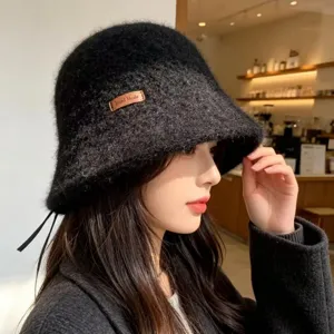 Detail view of the black knit bucket hat featuring side leather tag and warm texture.