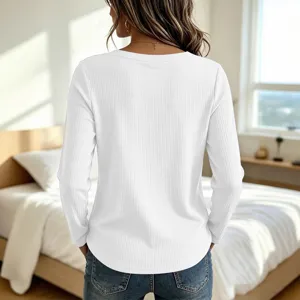 Back view of a casual white long sleeve waffle ribbed top paired with jeans in bedroom.