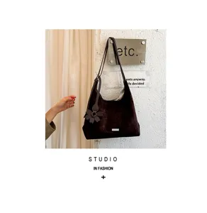 Λεπτομερης οψη vintage καφε τσαντας tote απο σουεδ με κρεμαστο λουλουδι στο σκηνικο.