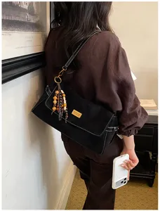Vue détaillée du sac porté épaule noir rétro avec un charmant pompon de perles stylé.