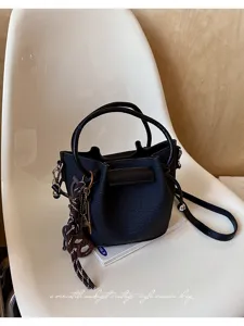 Λεπτομέρεια μαύρη δερμάτινη τσάντα bucket, vintage χιαστί τσάντα με λαβή και κομψό charm.