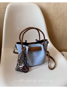 Κομψή τσάντα bucket από denim με καφέ δερμάτινες λαβές και chic λεπτομέρειες για κάθε μέρα.