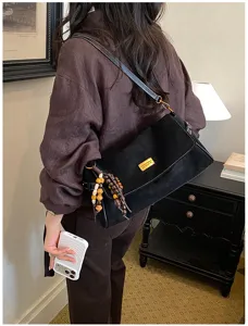 Sac porté épaule rétro en suédine pour femme avec pendentif perles bois et badge chic.